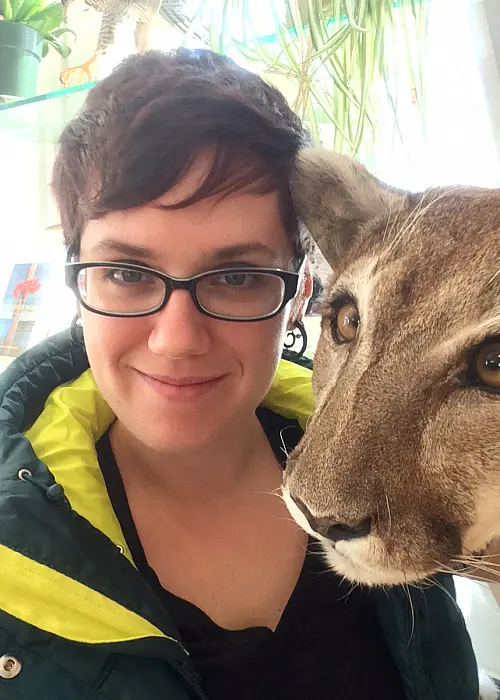 Image of Caucasian woman with short dark hair and glasses and in frame with large cat.