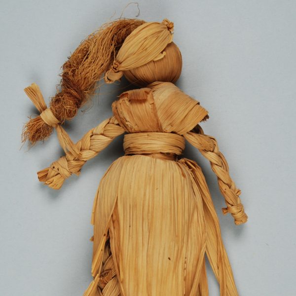 Image of a doll made of corn husks with braided arms and legs and cornsilk hair.