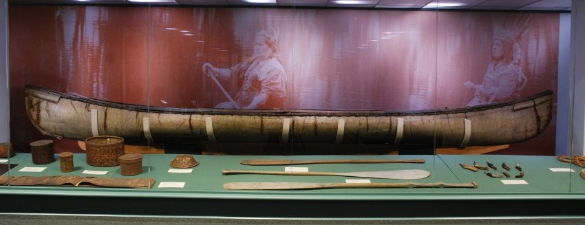 Image of a birchbark canoe in a museum case.