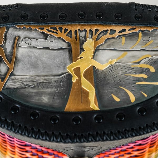 Detail of the top of a basket featuring an image made in metals. A man with a bow on the left, a man coming from a tree center.