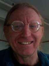 Image of Caucasian man with round glasses focusing on face alone.