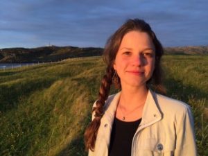 Image of Caucasian woman with brown hair in side braid standing outside.