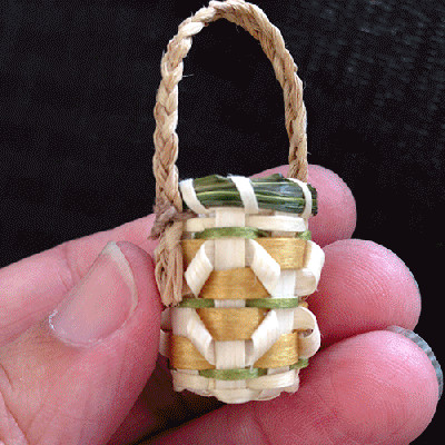 Image of hand holding tiny basket with curls and braided grass handle.