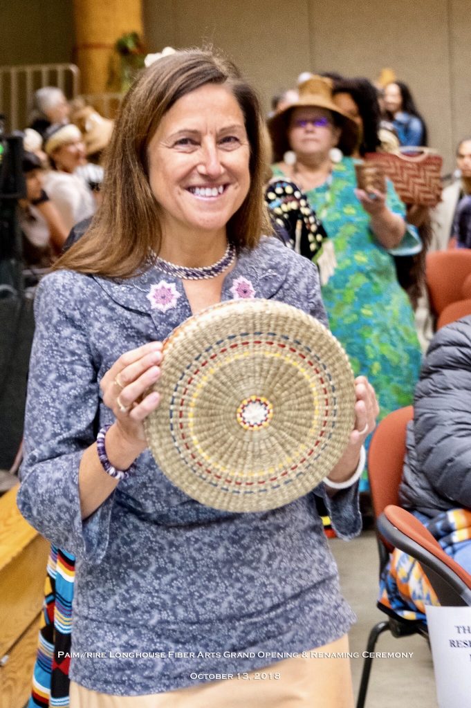 Image of a smiling woman wearing blue shirt holding round basket.