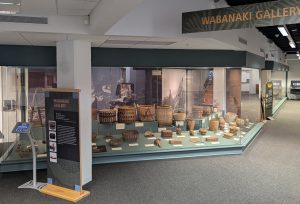 Image of a museum exhibit fill of baskets. Signs in the image read "Wabanaki Gallery".