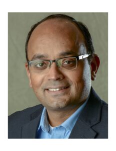 Image of South Asian man with short hair wearing glasses and a collared shirt and jacket.