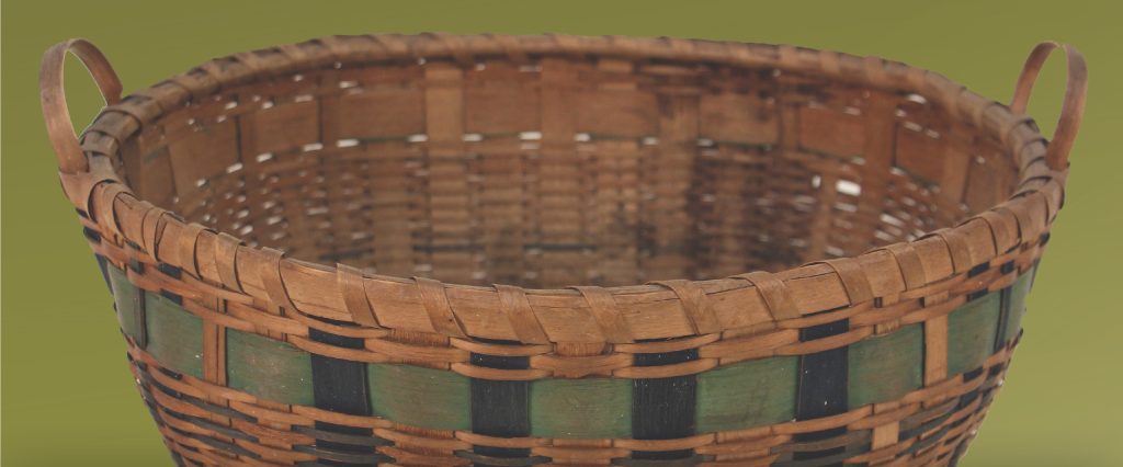 Detail shot of a basket with green band woven through dark blue weavers.