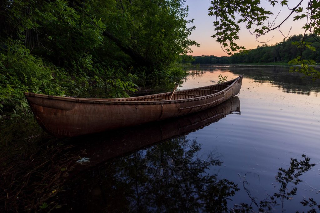 Sample of artist's photography: a canoe floating at a riverbank surrounded by greenery.