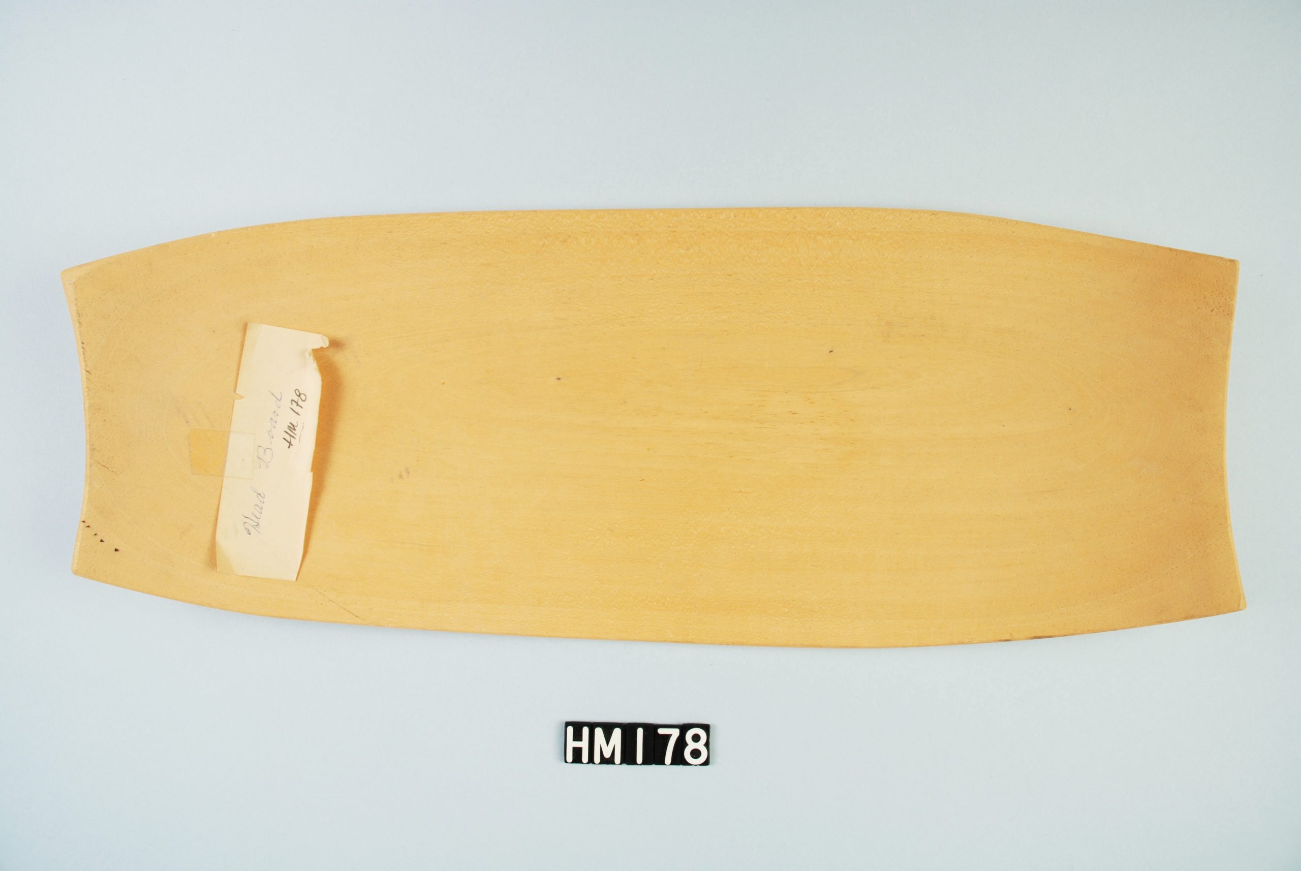 Image of flat wooden object slightly tapered at ends.