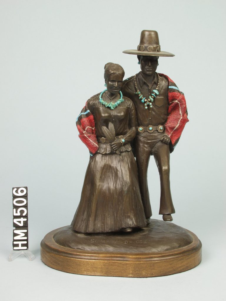 Image of a bronze statue of a couple in southwestern dress with red and turquoise accents.
