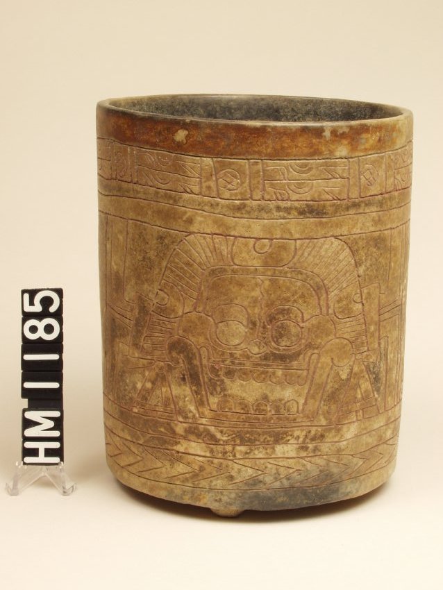Vase with vertical sides. Interior is black, rim painted with red band. Sides are incised with a death's head or skull.