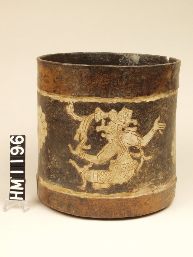 Wide vase with vertical walls. Decorated with an incised seated figure with anthropomorphic face painted white with a background field of black.