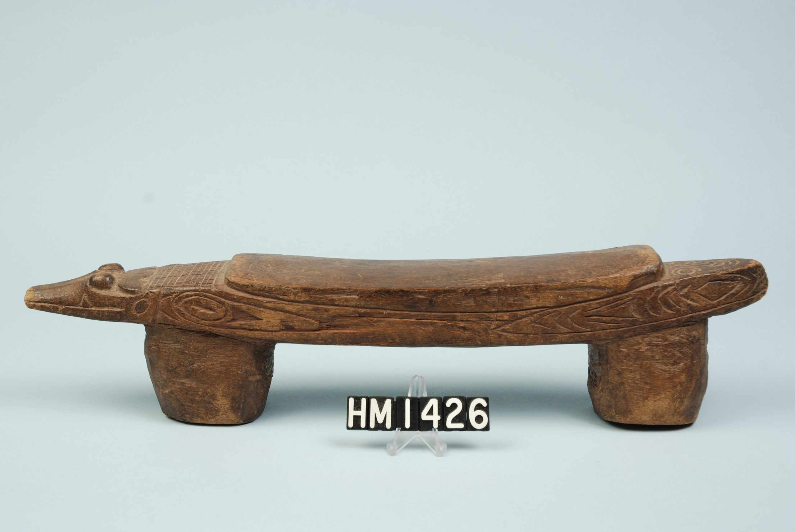 Image of a low wooden object shaped like an animal with the legs forming the supports.