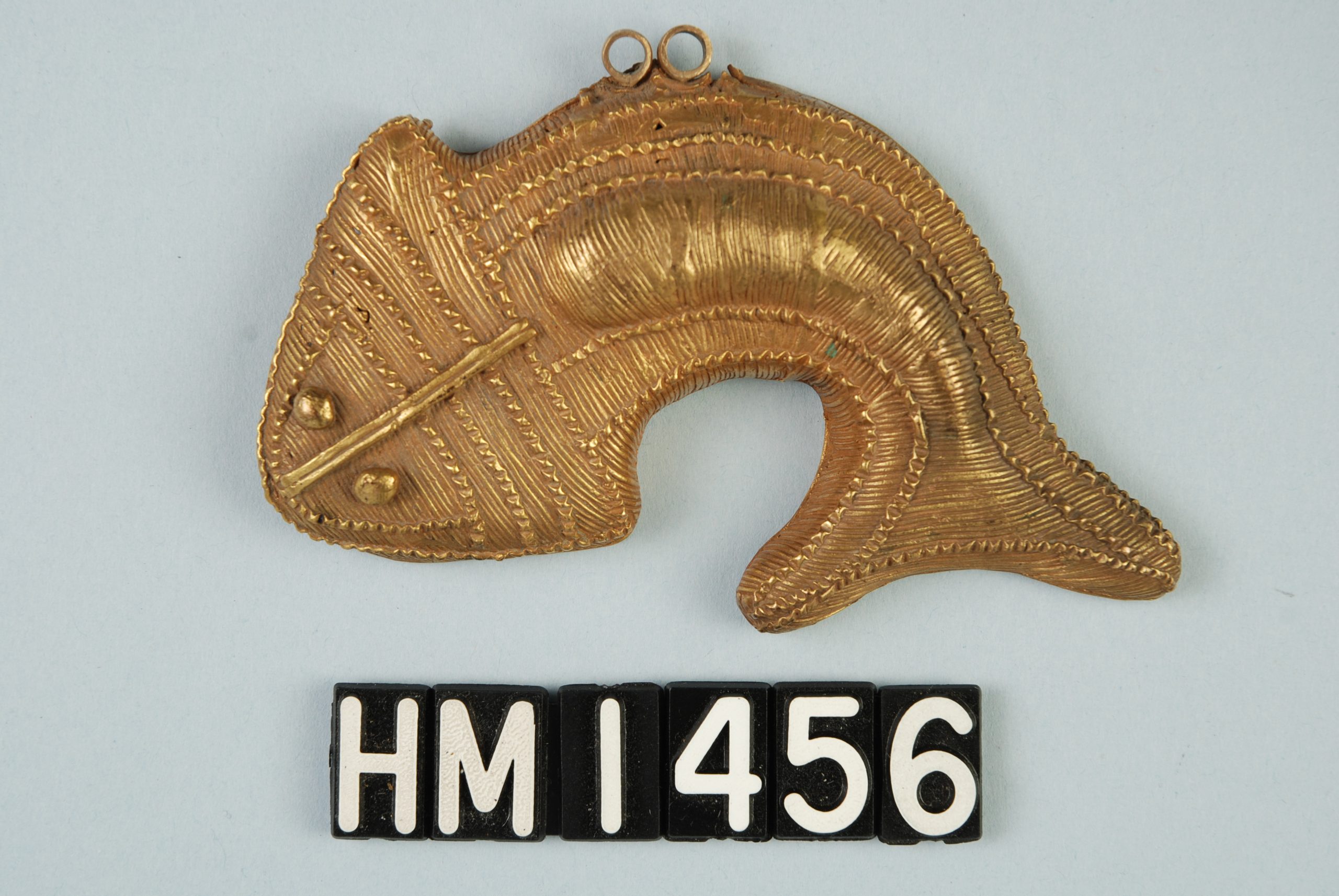 Image of a golden fish ornament with detail elements.