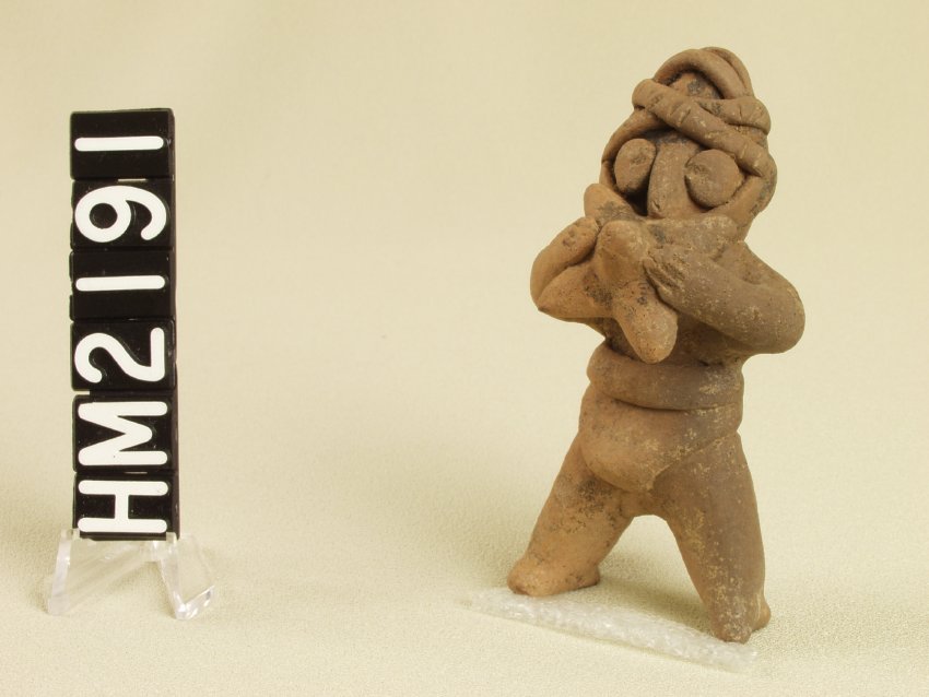 Tiny ceramic figure, simple, holding instrument to mouth with both hands.