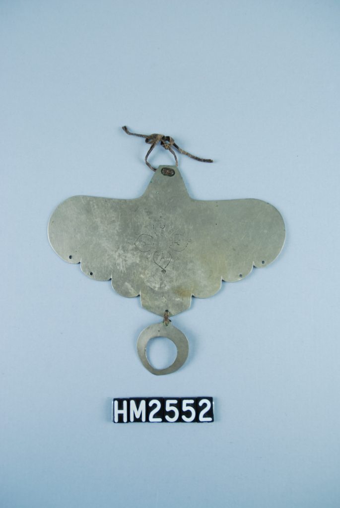 Image of silver ornament shaped like a moth with wings spread with a circle dangling from the bottom.