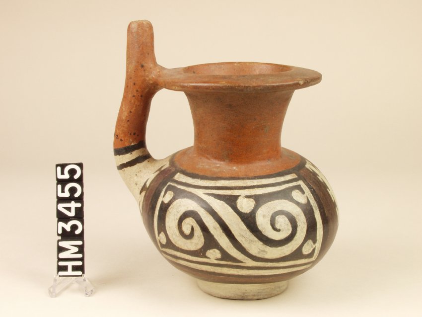 Miniature polychrome ceramic double-spouted carafe. Round body with white and black elements, red neck with lip. Handle attached at body and lip.