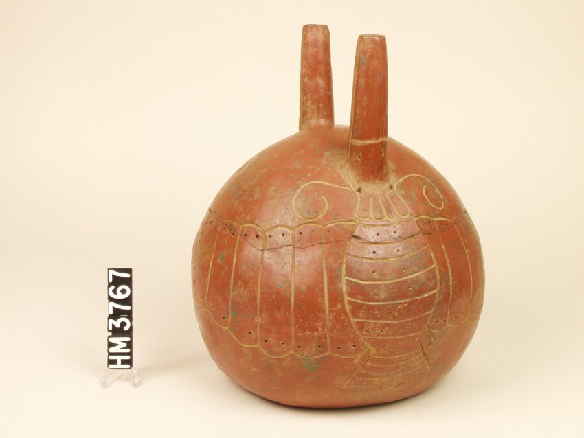 Ceramic vessel with globular body and two narrow spouts on top. Two incised hummingbird moths on either side with each spout serving as a beak. Hollow red-brown clay, painted red.