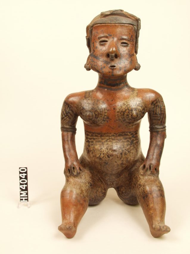 Seated ceramic figure with rounded belly. Painted red with body designs of black and cream. Has sprig-molded arm bracelet.