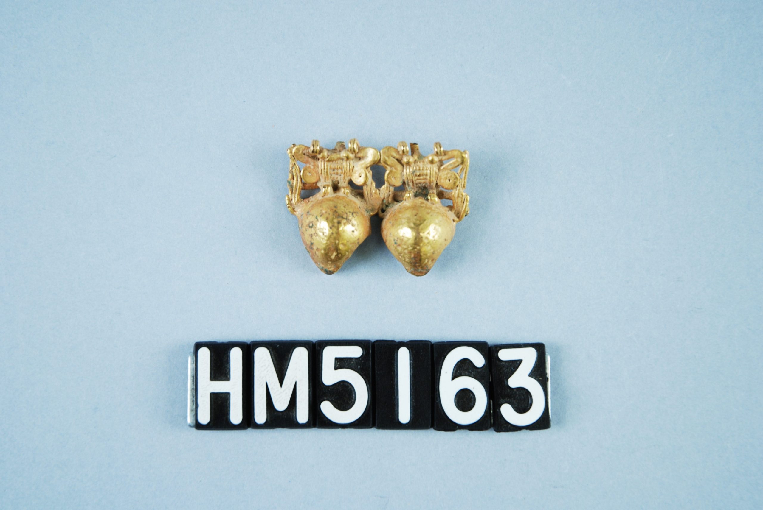 Delicate gold ornament, may represent a pair of frogs with large heads and characteristically flexed legs.