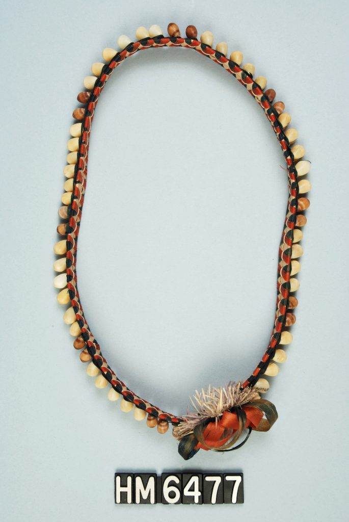 Image of ornament made with shells attached to woven band with bow.