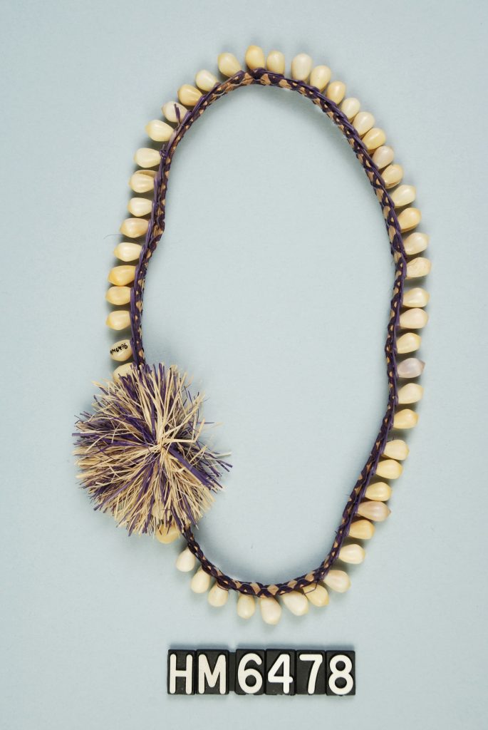 Image of ornament made with shells attached to woven band with pompom.