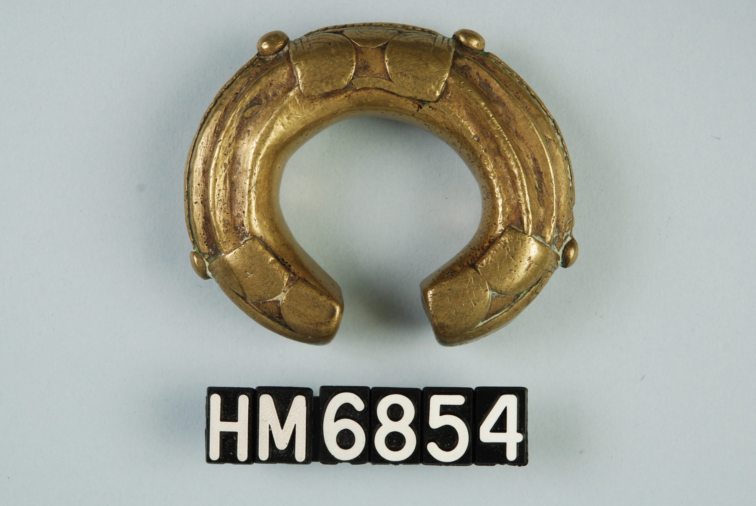 Image of a thick brass bracelet with applied details.