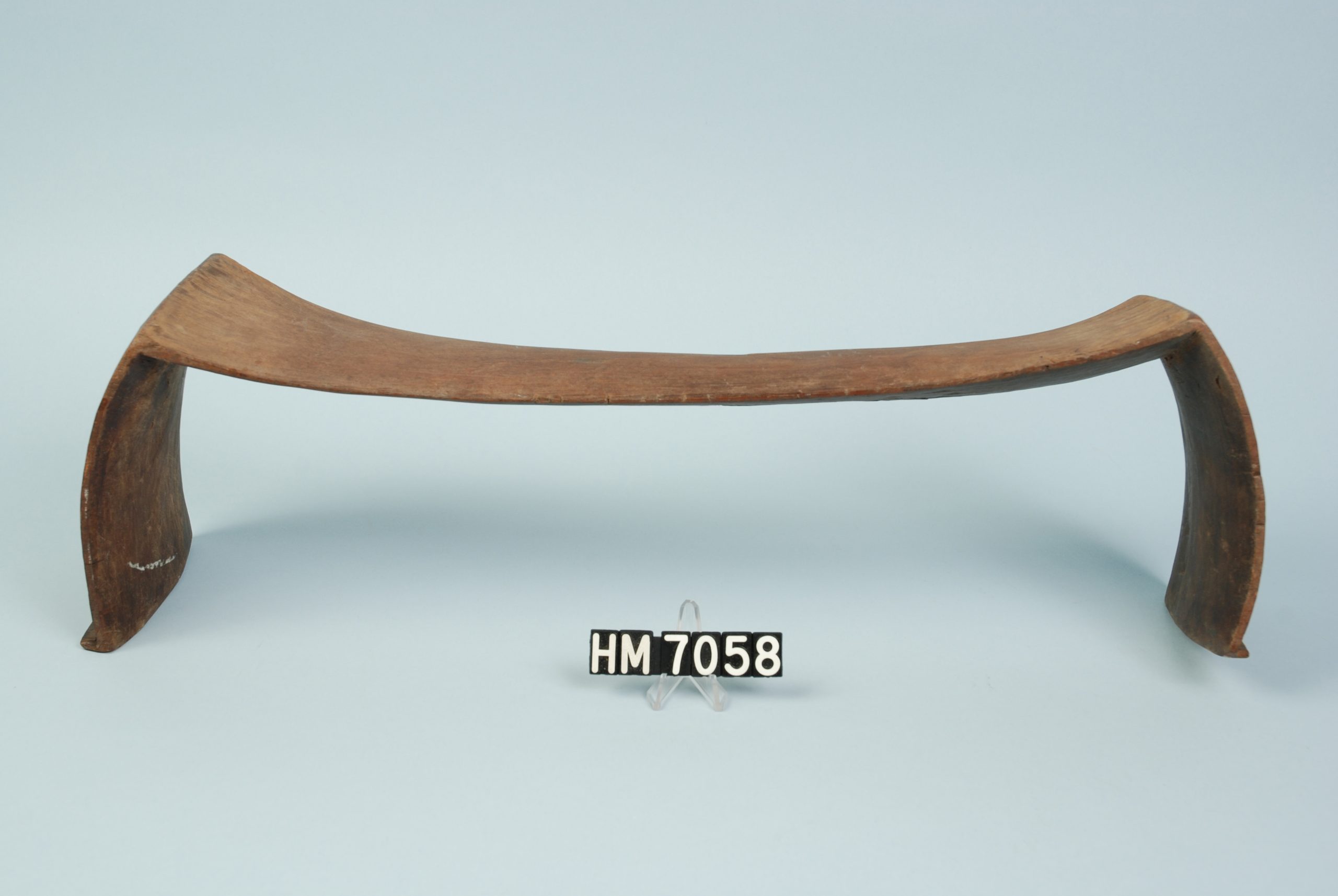Image of a low wooden object, wider than it is tall, made of a single piece of wood bent down to be legs at each end.