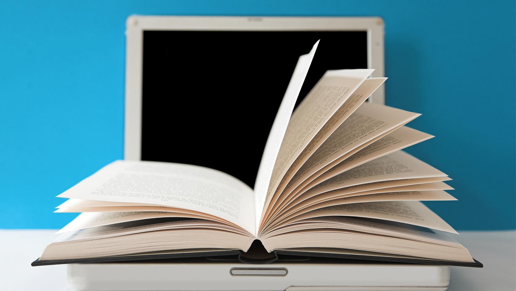 An open book on the keyboard of a laptop