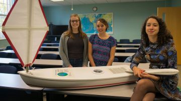 Members of the Marine Sciences Club post with a miniboat