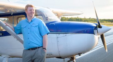 UMaine student stands in front of an airplane