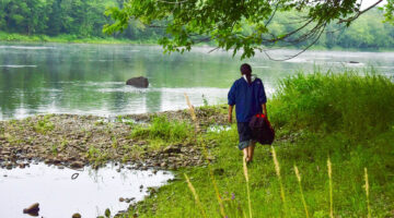 A person walks next to a river