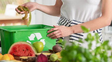 A woman puts food into a recycling container