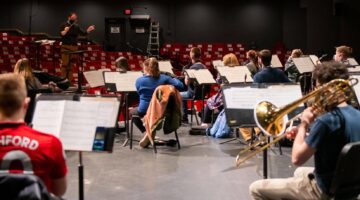 Conductor directs students in the University of Maine Symphonic Band as they play their instruments.