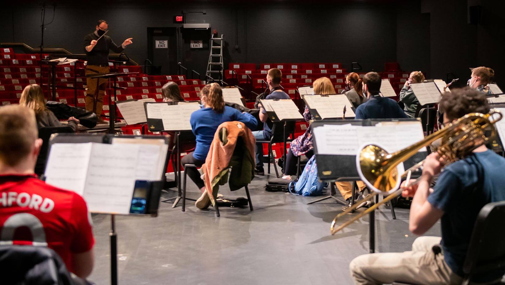 Conductor directs students in the University of Maine Symphonic Band as they play their instruments.