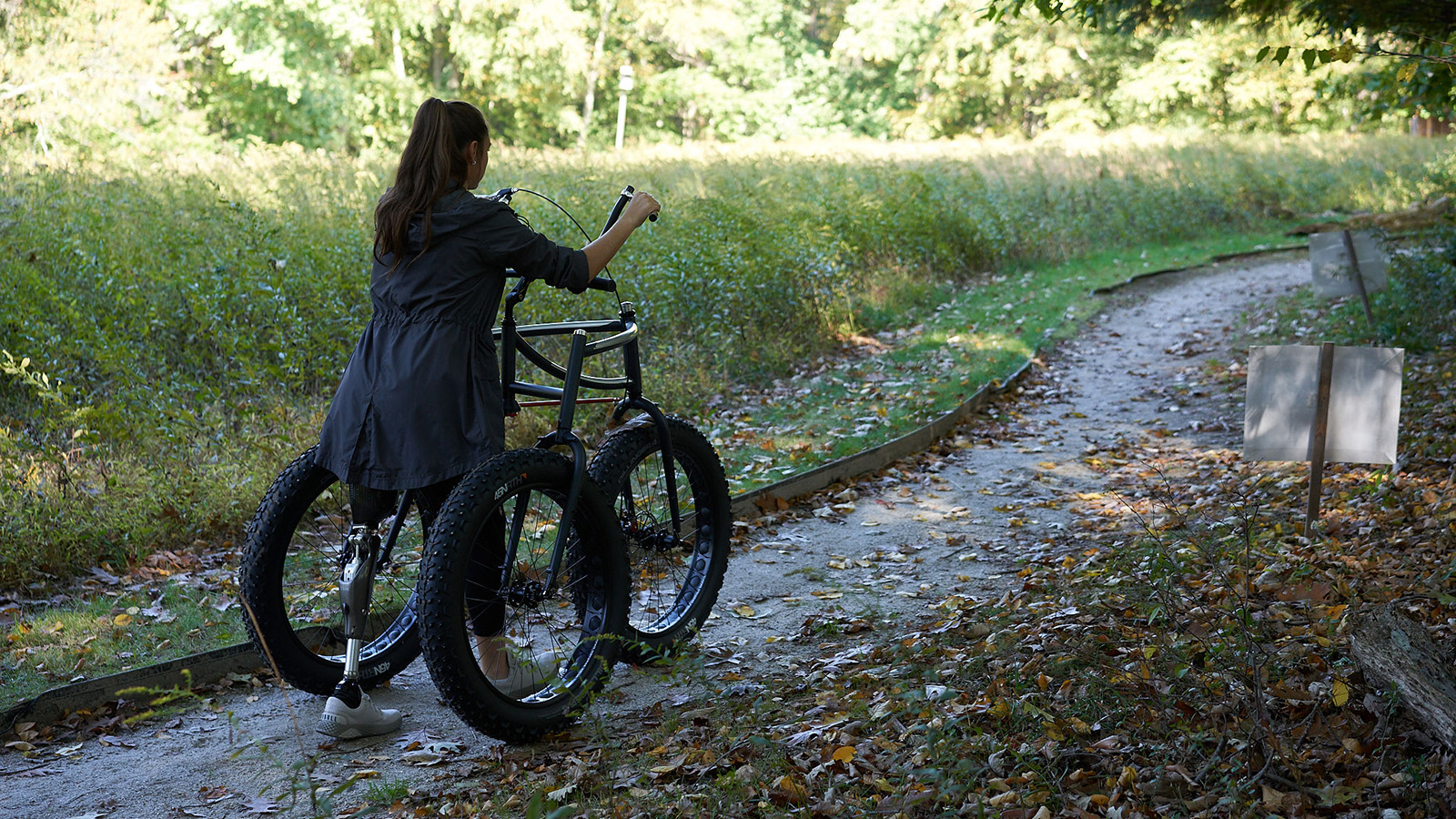 An Afari mobility bike being used on a path by a rider with a prosthetic leg