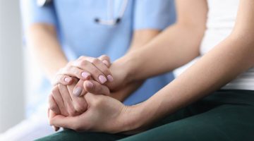 A photo of a doctor holding hands with a patient