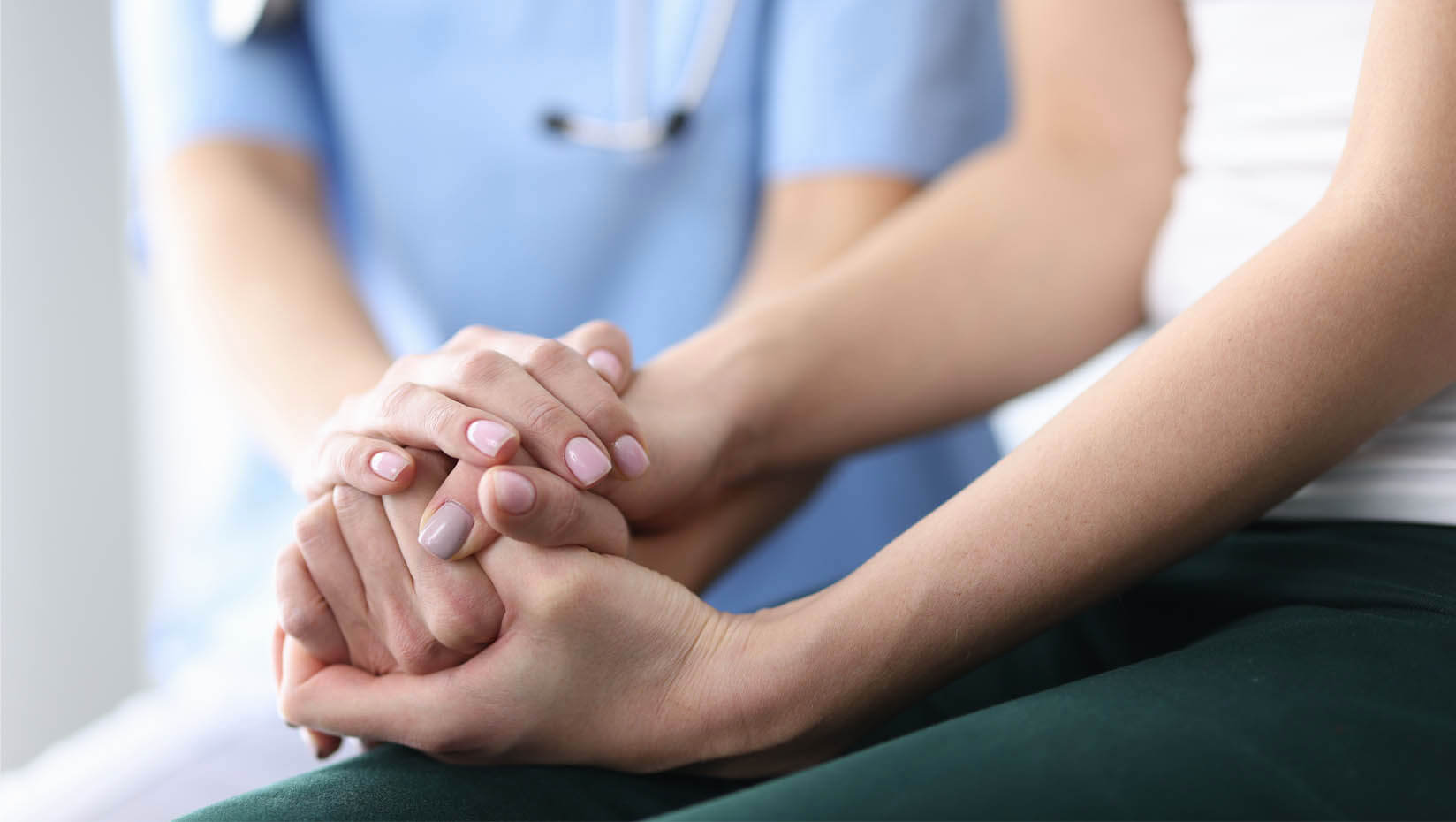 A photo of a doctor holding hands with a patient