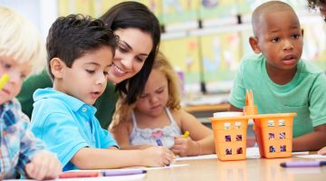 A photo of a teacher and young students in a classroom