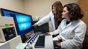 A photo of two people looking at a computer monitor
