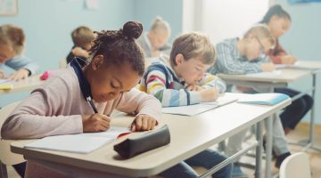 A photo of elementary school students writing at desks