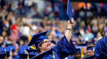 A photo of a graduate holding up her diploma
