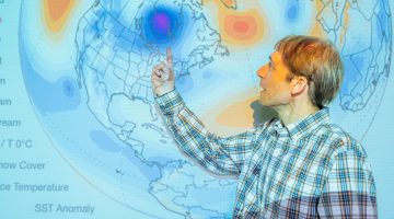A photo of Sean Birkel standing in front of a projection of a Climate Reanalyzer map