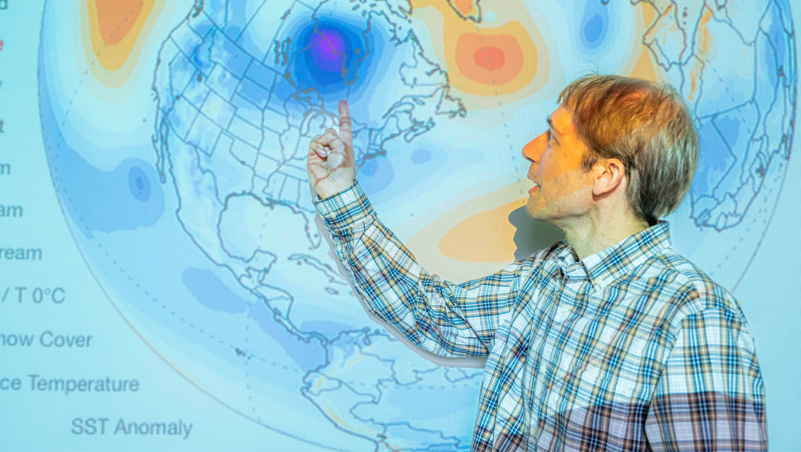 A photo of Sean Birkel standing in front of a projection of a Climate Reanalyzer map