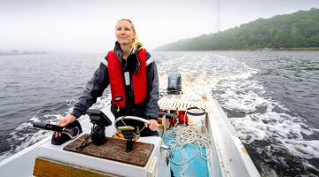 A photo of Lauren Ross steering a boat on the Maine ocean
