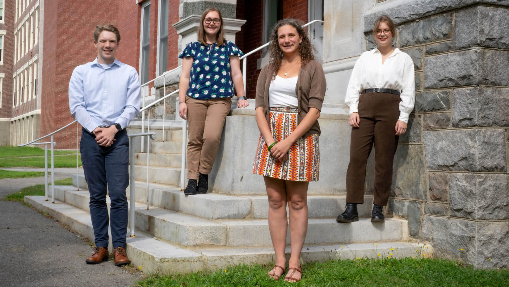 A photo of four student fellows in front of a brick building