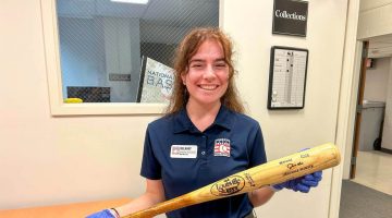 A photo of Delaney Colson holding a bat at a museum