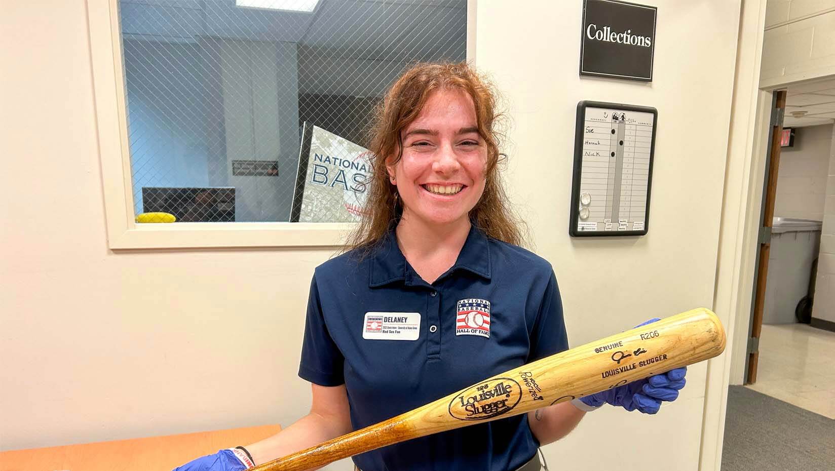 A photo of Delaney Colson holding a bat at a museum
