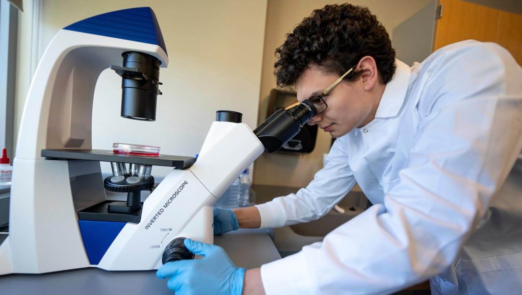 A photo of an engineering student looking in a microscope