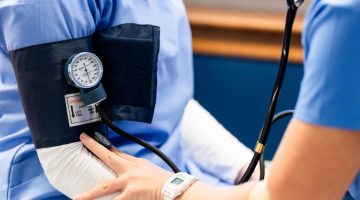 A photo of a nursing checking another nurse's blood pressure